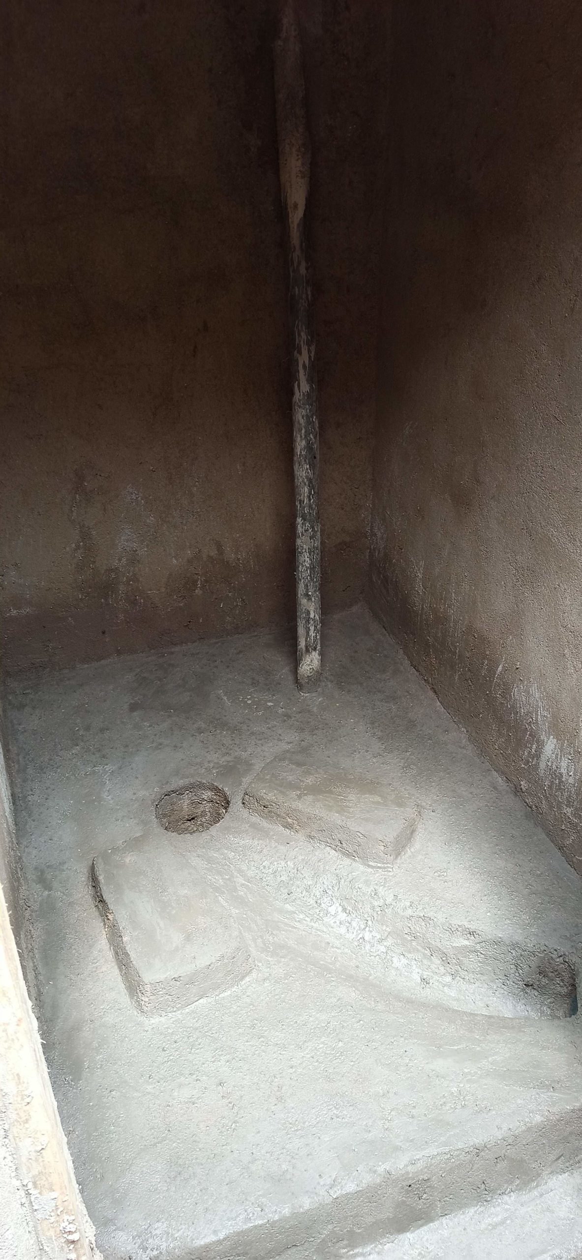 Inside of a household latrine showing a concrete slab with a whole in the back for faeces and a whole in the front for urine collection